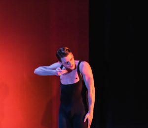 Ballet BC dancer Justin Rapaport with black bodysuit, orange lighting.