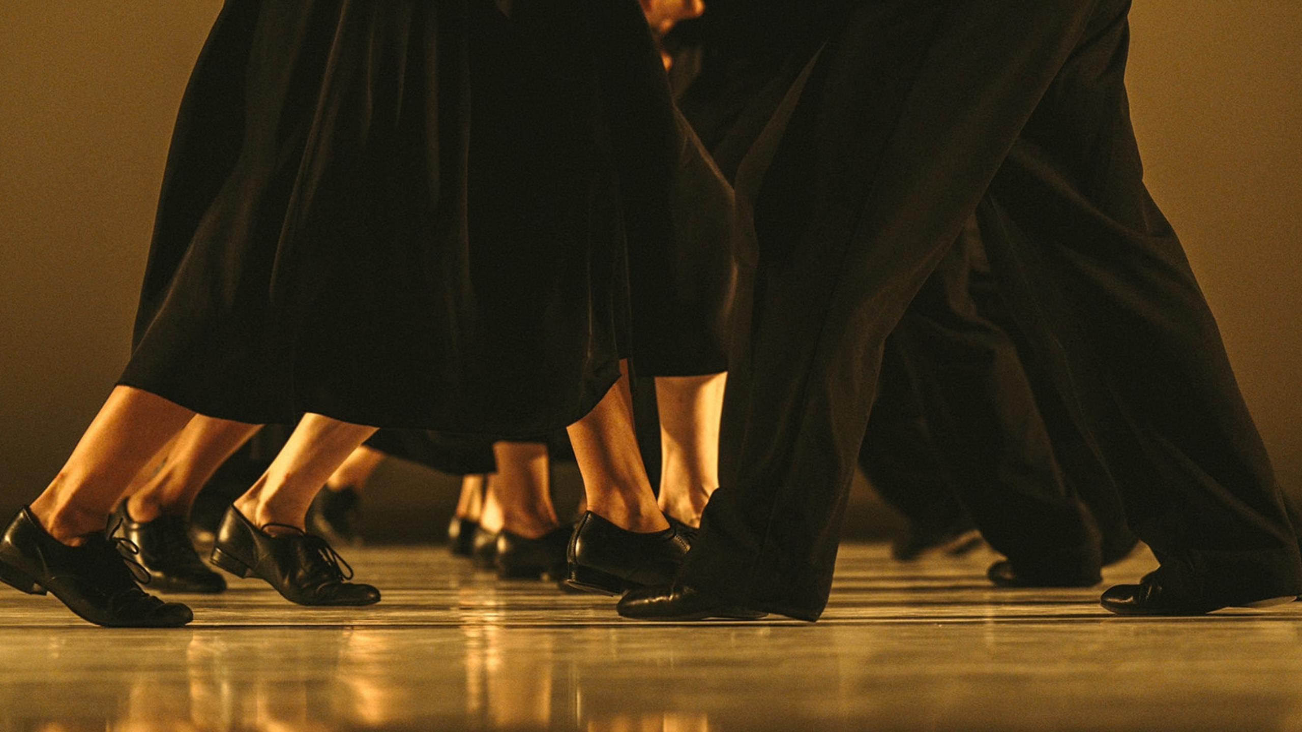Dancers in black shoes perform on stage