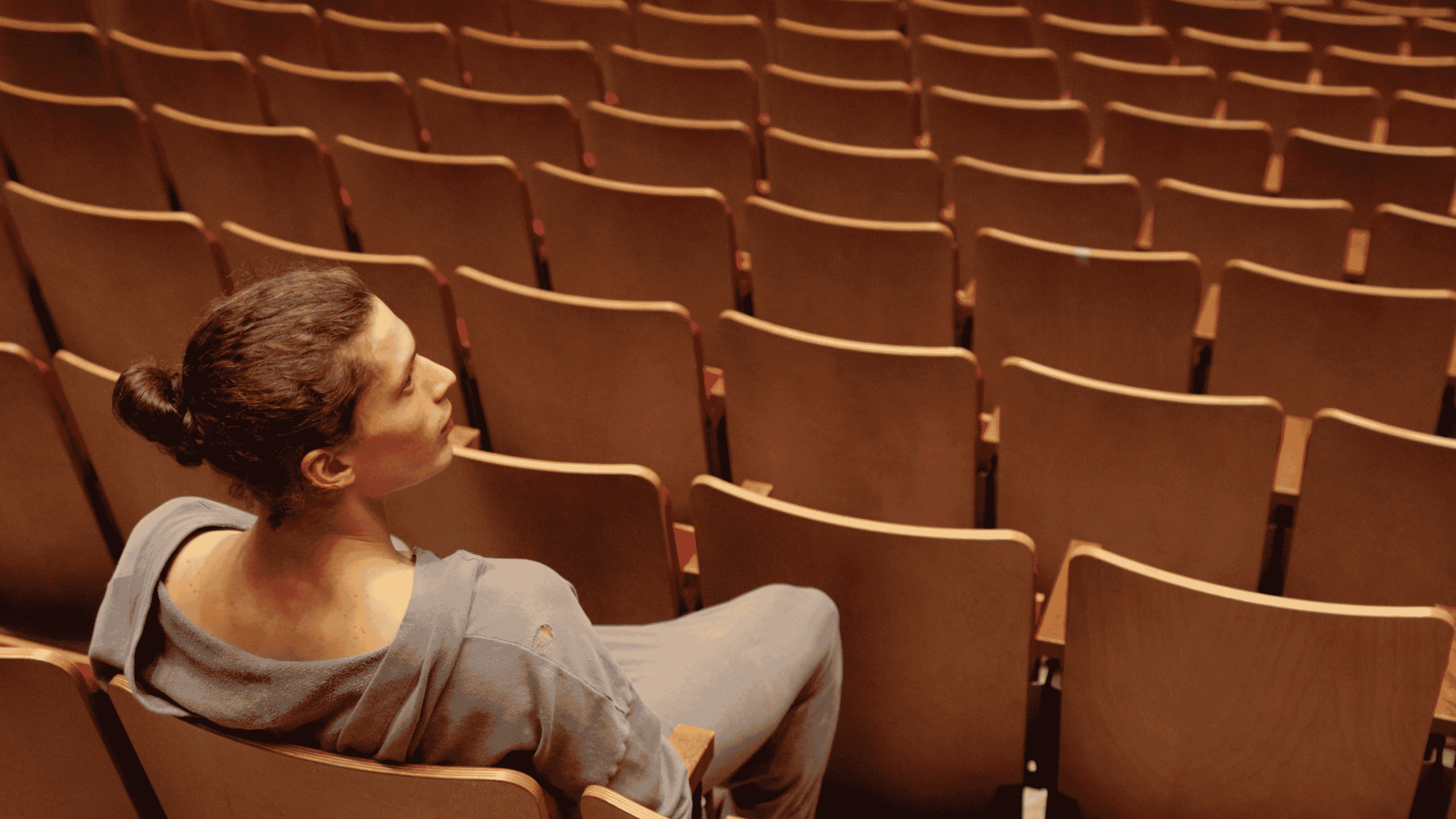A dancer sits in an empty theatre.