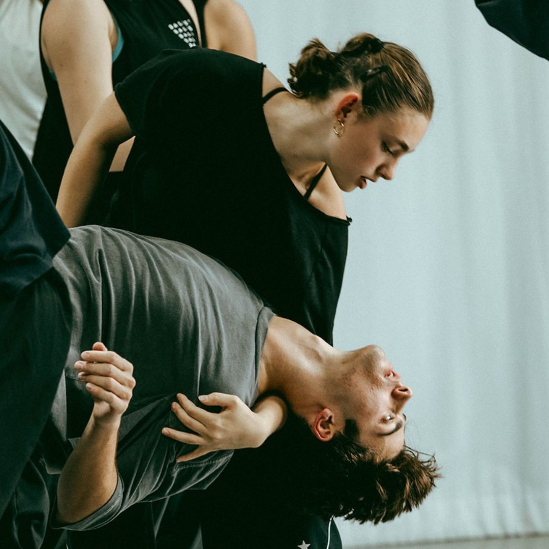 Two dancers partner in a bright studio.